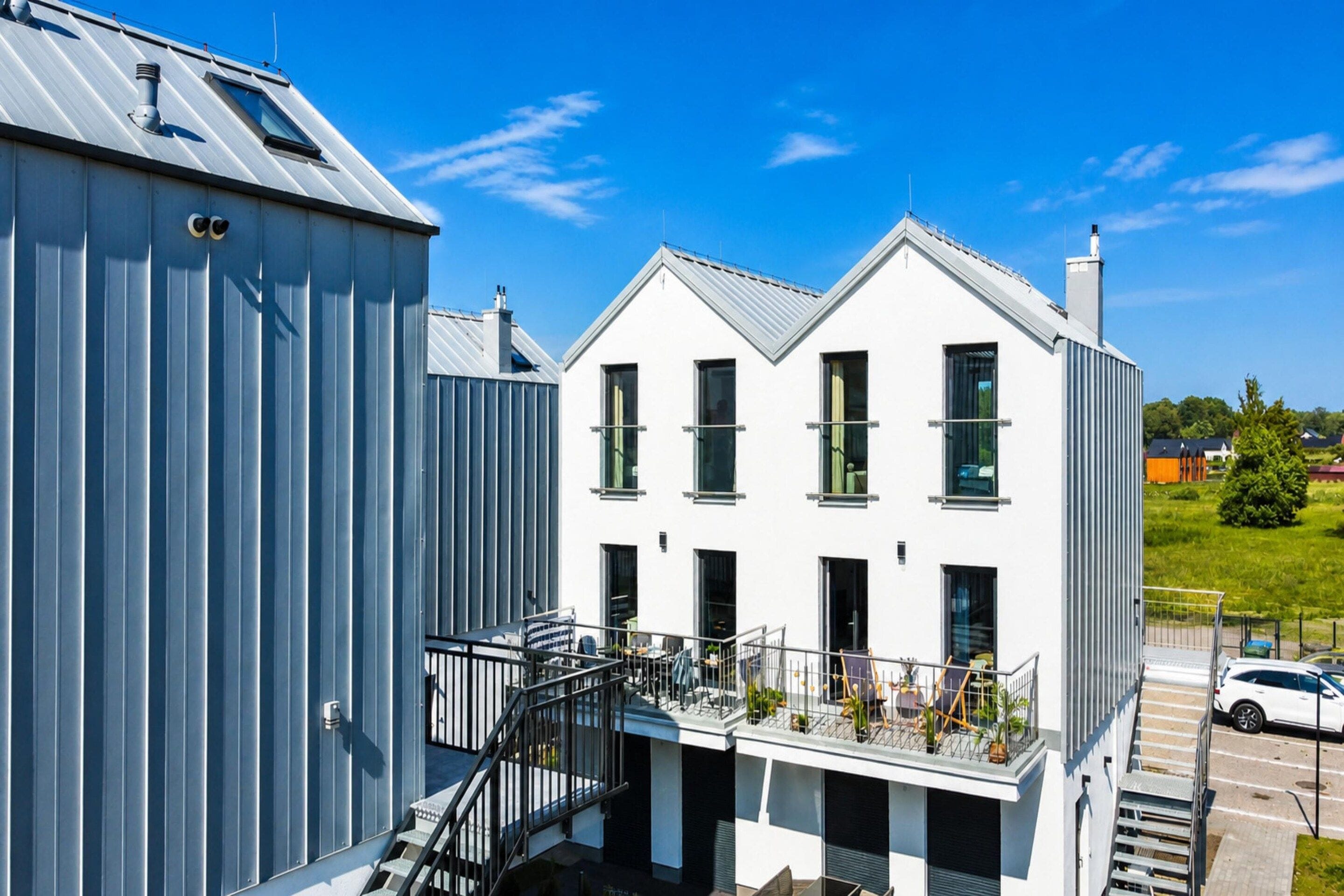 A modern two-story building with a balcony and a staircase leading to the upper floor.