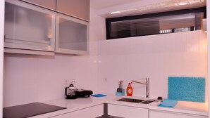 A modern kitchen with white cabinets, a stainless steel sink, and a microwave above the counter. - Douro Apartments - Luxuryviews (Vila Nova de Gaia)