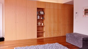 A room with a large wooden wardrobe, a grey sofa, and a grey rug. - Douro Apartments - Luxuryviews (Vila Nova de Gaia)