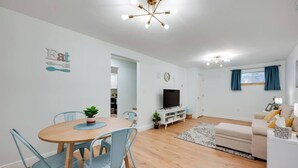 En moderne stue med spiseplads, fjernsyn og sofa.