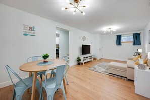 Ein modernes Wohnzimmer mit Essbereich, Fernseher und Sofa.