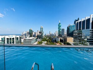 En swimmingpool med byens skyline i baggrunden.