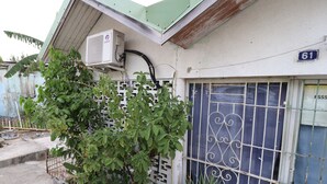 Um edifício com telhado verde, placa com o número '61', janela com grades e uma placa que diz 'CARS'.