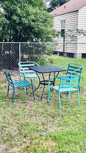An outdoor seating area with a metal table and chairs, surrounded by a chain-link fence. - Steps2White Sandy beach/Familyfun/fishing/Games (Gulfport)