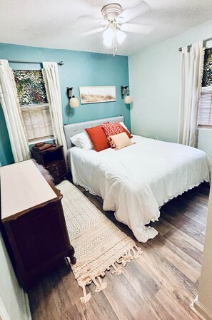 A bedroom with a bed, a nightstand, a dresser, a ceiling fan, and a window with curtains. - Steps2White Sandy beach/Familyfun/fishing/Games (Gulfport)