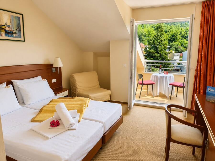 Een hotelkamer met een bed, een stoel, een tafel en een balkon met uitzicht.