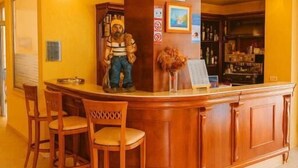 Zona de recepción con mostrador de madera, un reloj y una estatua. Hay tres sillas de madera frente al mostrador.
