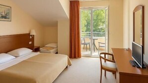 Habitación de hotel con cama, escritorio, televisión y vistas al exterior.