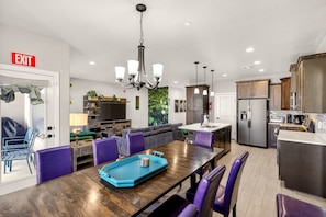 A modern kitchen with a dining area, a chandelier, and a refrigerator. - 5BR Utah Escape Near Zion – Pool and Grill (Hurricane)