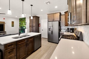 A modern kitchen with a central island, stainless steel appliances, and wooden cabinets. - 5BR Utah Escape Near Zion – Pool and Grill (Hurricane)