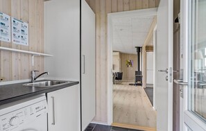 A modern kitchen with a sink, stove, and a wooden wall with informational posters.