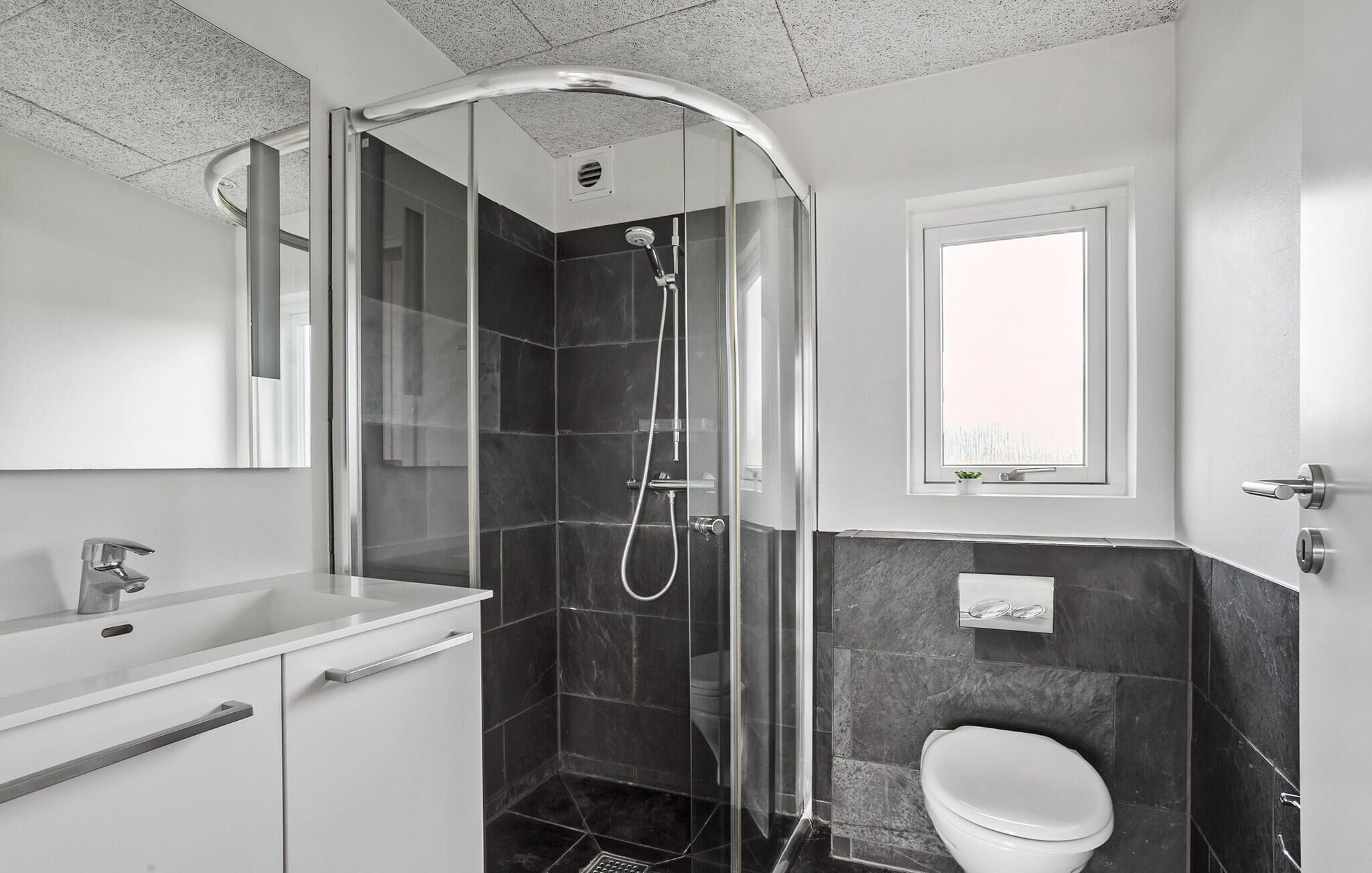 Un bagno moderno con cabina doccia in vetro, lavandino bianco e water.