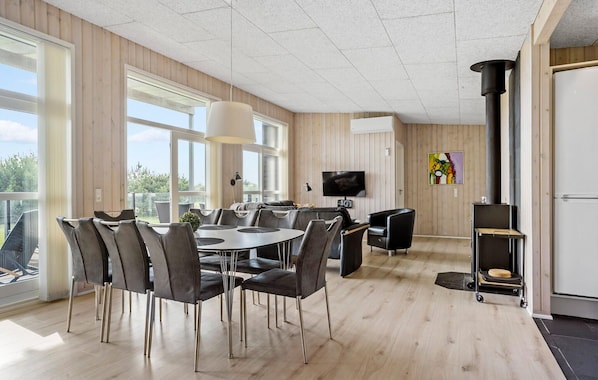 Un interior moderno con comedor, asientos, televisor y chimenea.