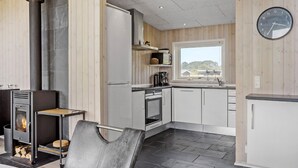 Moderni keittiö, jossa on sisäänrakennettu liesi, ruokailutila tuolilla ja näkymä ikkunasta.