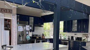 Une cuisine moderne avec des meubles de couleur bleu foncé, un plan de travail blanc et un coin bar avec des tabourets.