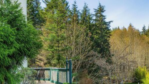 Une terrasse en pierre avec un foyer, deux chaises et une terrasse en bois dotée d’une rambarde.