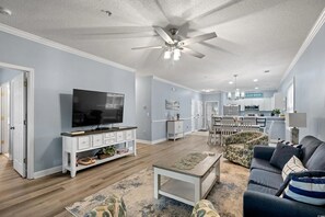 Ein Wohnzimmer mit Fernseher, Sofa, Couchtisch und Deckenventilator.