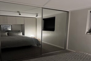 Une chambre à coucher comprenant un lit, une porte coulissante, une fenêtre et un luminaire fixé au mur.