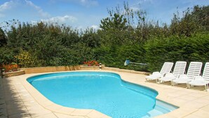 Ein Schwimmbecken mit gewölbter Kante, umgeben von einer gefliesten Terrasse.