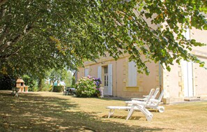 A building with a garden, outdoor seating, and a tree providing shade. - Awesome home in Ginestet with WiFi (Ginestet)