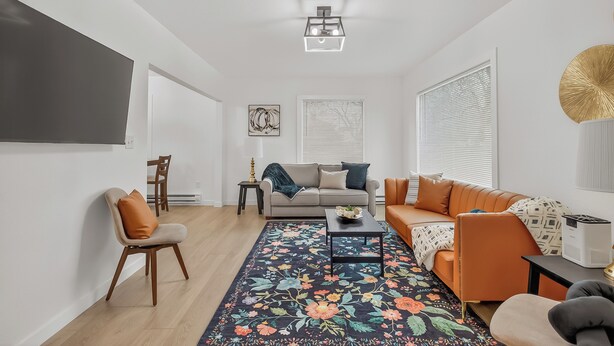 A modern living room with a sofa, armchairs, a coffee table, and a patterned rug.