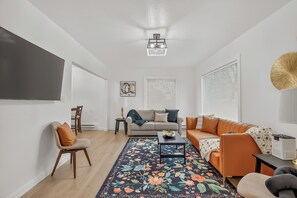 Un salon moderne avec un canapé, des fauteuils, une table basse et un tapis à motifs.