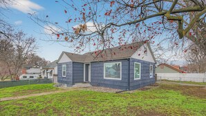 A small house with a sloped roof, a front porch, and a fenced yard.