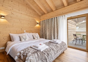 A wooden-paneled bedroom with a bed, pillows, and a large window. - Luxury Apartment, 1 Bedroom Rahas B Grimentz - By Mrs Miggins (Grimentz)