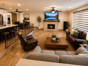 Ein modernes Wohnzimmer mit Kamin, Ledersofas, einem Essbereich und einem großen Fernseher.