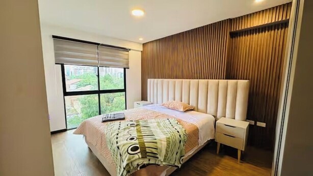 Un dormitorio moderno con una cama grande, una mesita de noche, una ventana con persianas y un panel de pared de madera.
