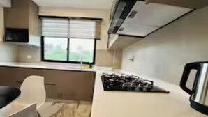 Una cocina con estufa a gas, microondas y ventana con persianas.