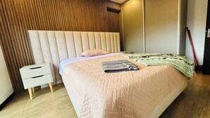 Un dormitorio con cama, mesita de noche y paneles de madera en la pared.