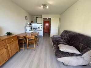 A compact living space with a kitchenette, a dining area, and a sofa. - AS27185 - Studio apartment with sleeping alcove, 200m from the beach, with parking and air... (LE GRAU DU ROI)