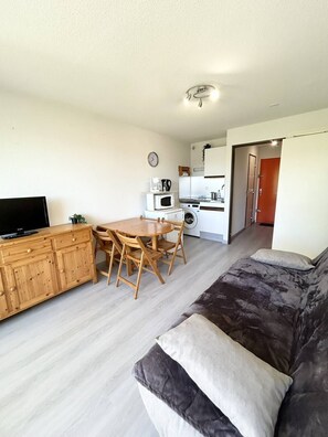 A compact living space with a kitchenette, a dining area, a sofa, and a TV. - AS27185 - Studio apartment with sleeping alcove, 200m from the beach, with parking and air... (LE GRAU DU ROI)