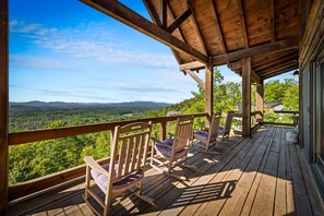 Eine Holzterrasse mit Stühlen mit Blick auf eine bewaldete Landschaft.