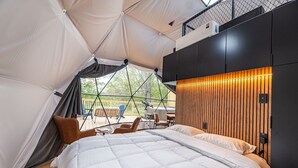 A tent-style room with a bed, wooden panel wall, and a view of the outdoors.