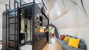A modern interior with a black metal wardrobe, a grey sofa with colorful cushions, and a tent-like structure in the background.