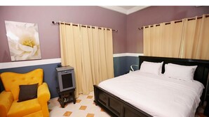 Una camera da letto con un letto, un comodino, una sedia e tende.