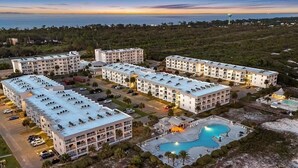 Un hotel su più piani con piscina, parcheggio e vista sull'oceano.