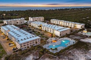 Ein mehrstöckiges Hotel mit Pool, Parkplatz und Meerblick.