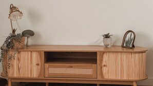 Un meuble en bois avec un panier tressé, une plante en pot et un tableau encadré.