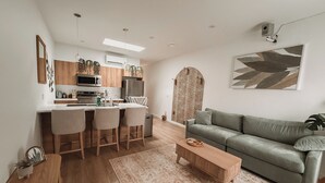 Une cuisine moderne avec un coin bar, un canapé gris et une table basse en bois.