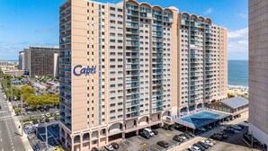 A multi-story hotel with a prominent 'Capri' sign, a parking lot, and a view of the ocean. - 2 Bedroom Condo W/ View of Bay & Ocean (Ocean City)