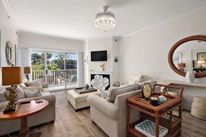Ein Wohnzimmer mit Kamin, Fernseher und einem Balkon mit Blick.