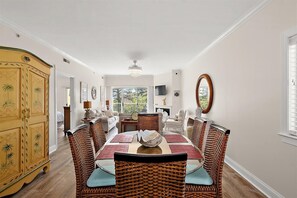 Ein Esszimmer mit großem Tisch, Korbstühlen, einem Holzschrank und Blick ins Freie.