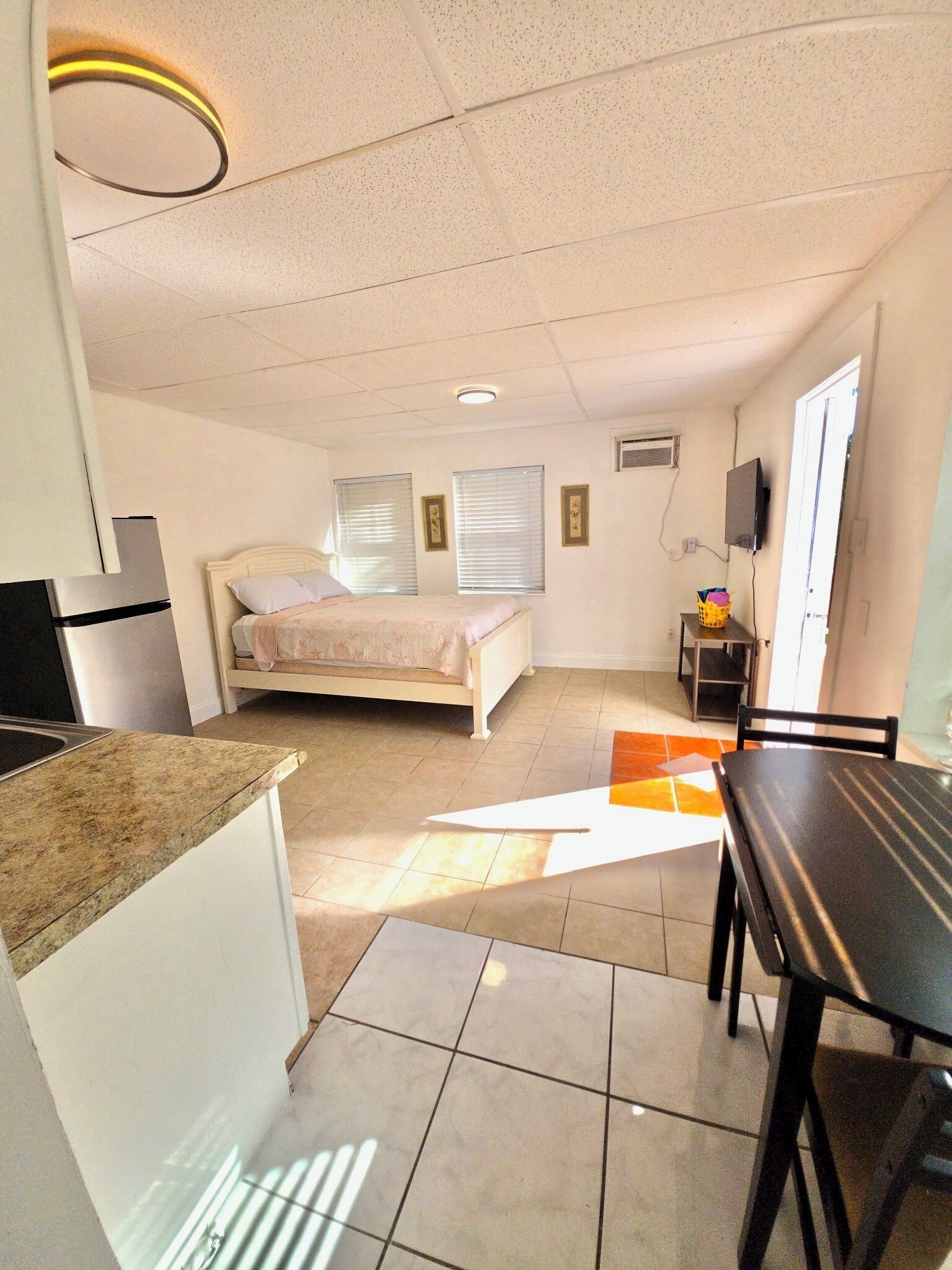 Ein kleines Zimmer mit Bett, Küchenzeile, Essbereich und Fernseher.
