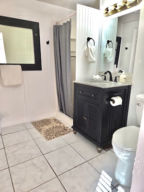 Ein Badezimmer mit Spiegel, Waschbecken, Toilette und Duschvorhang.