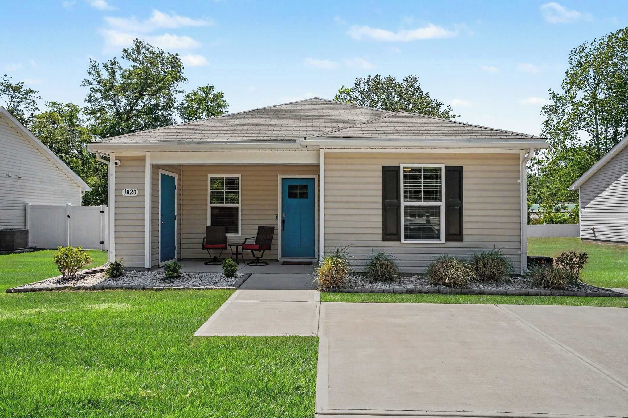 A single-story house with a front porch, a blue door, and a number '1820' on the side.