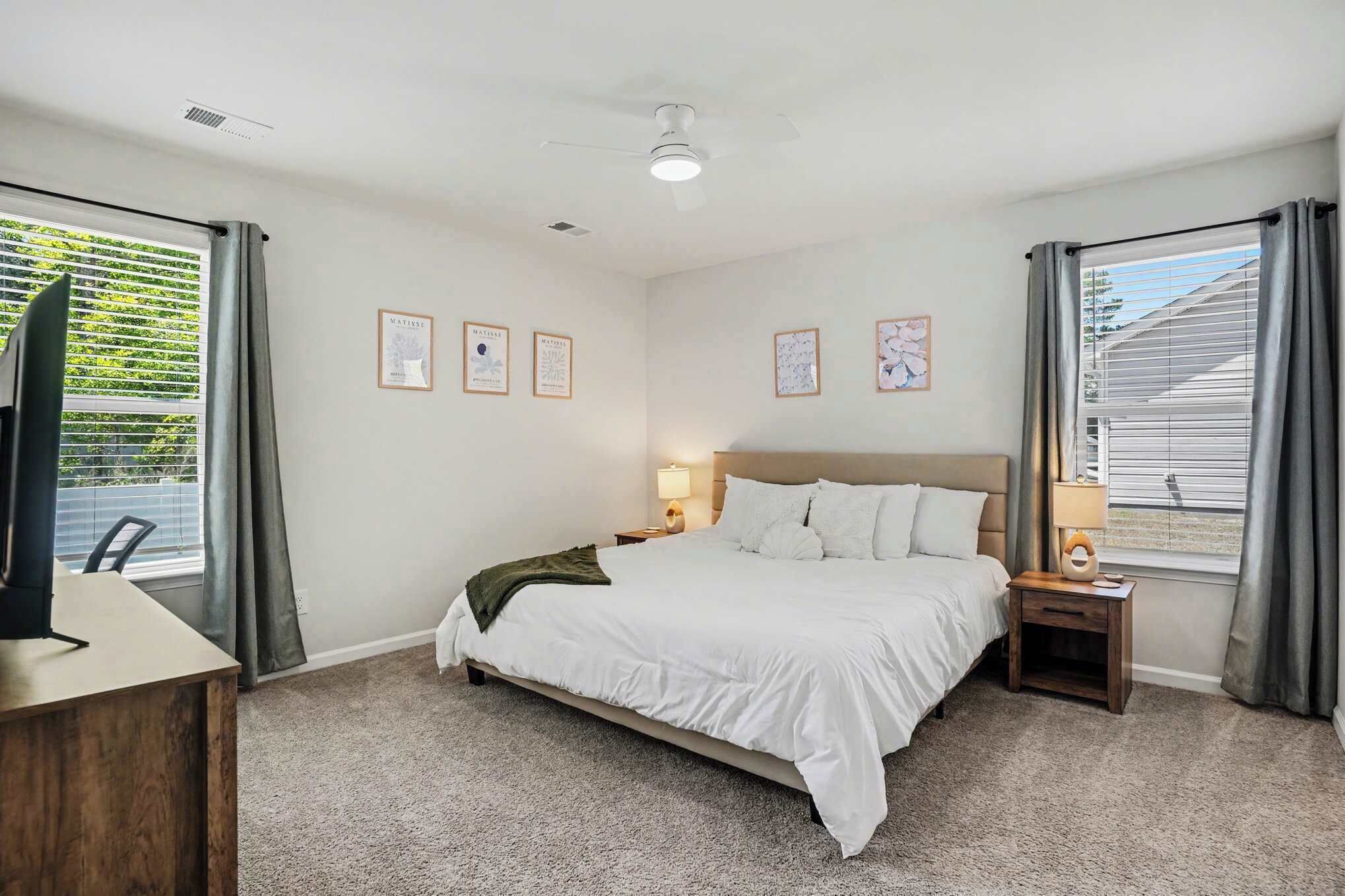 Une chambre à coucher avec un lit, des tables de chevet, un bureau et un téléviseur.
