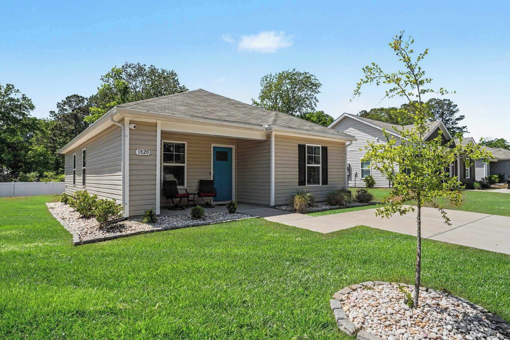A single-story house with a front porch, a mailbox, and a small tree in the front yard.